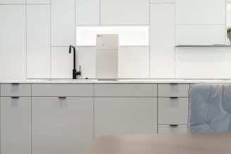 A sleek kitchen countertop featuring a modern under-the-sink reverse osmosis water filter with a glass of crystal-clear water beside it.