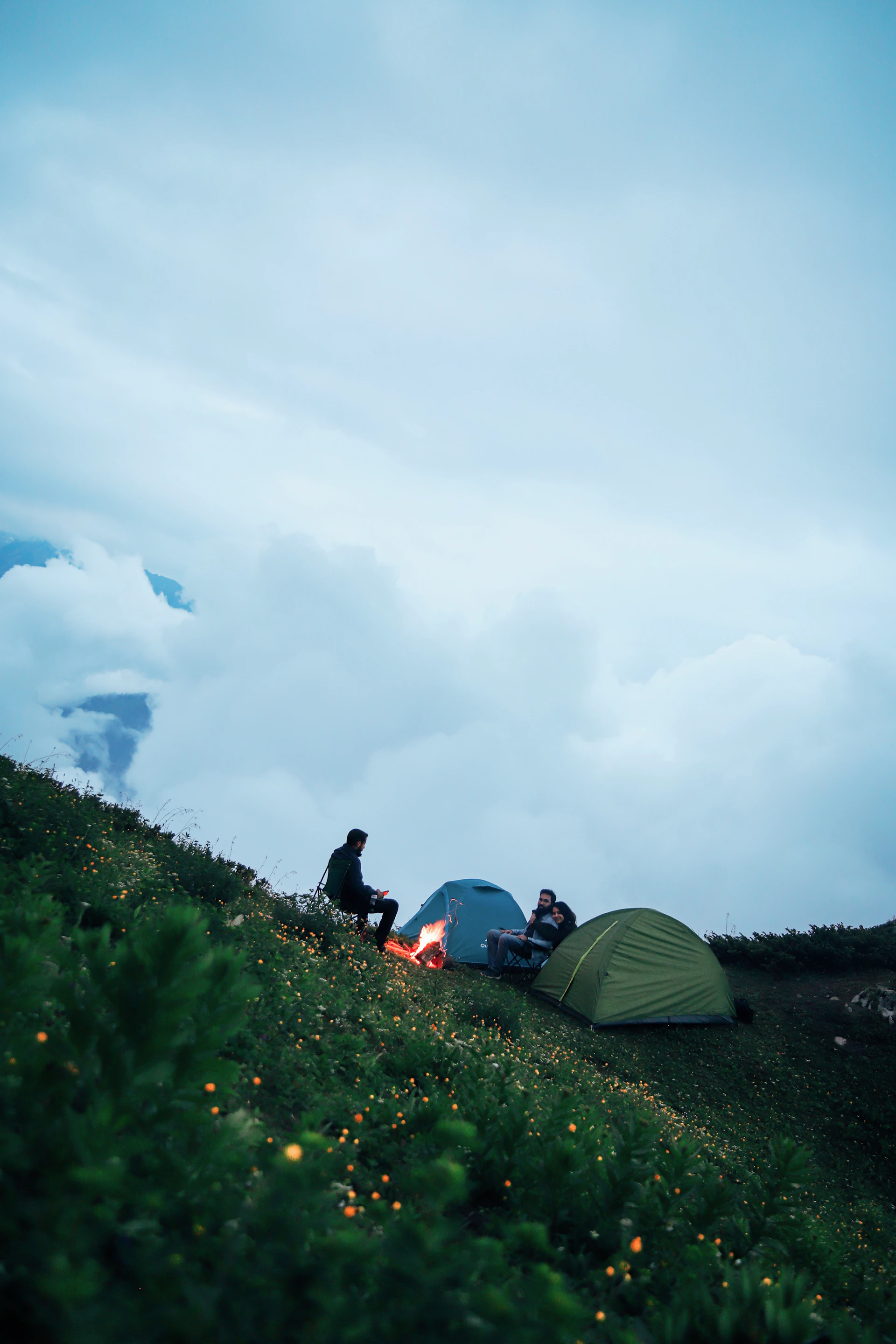 a group of people sitting in a grassy field next to a tent