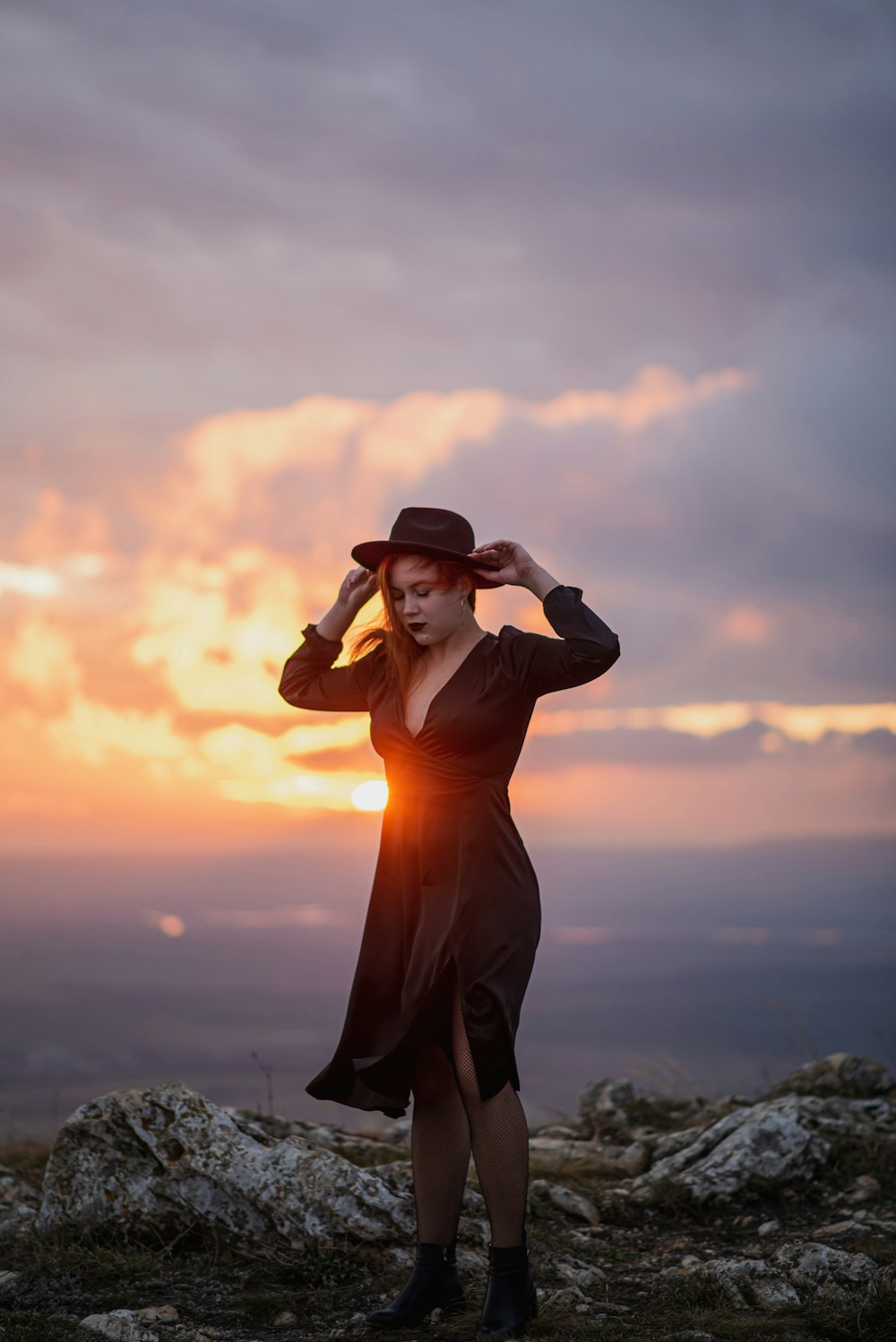 a man in a red dress and hat standing on a rocky hill