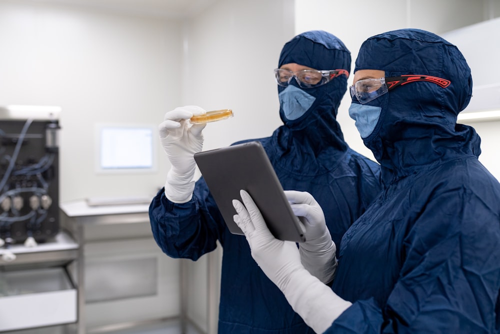 a couple of people wearing masks and gloves and holding a tablet