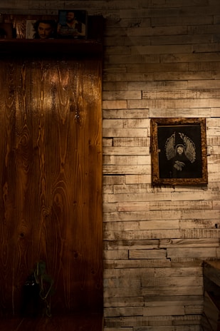 A cozy room corner featuring framed mythical creature art hanging above a wooden shelf.