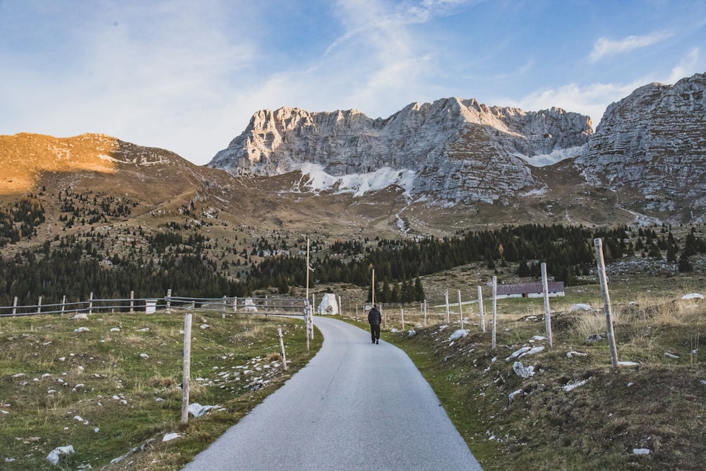 a road with a fence and mountains in the background