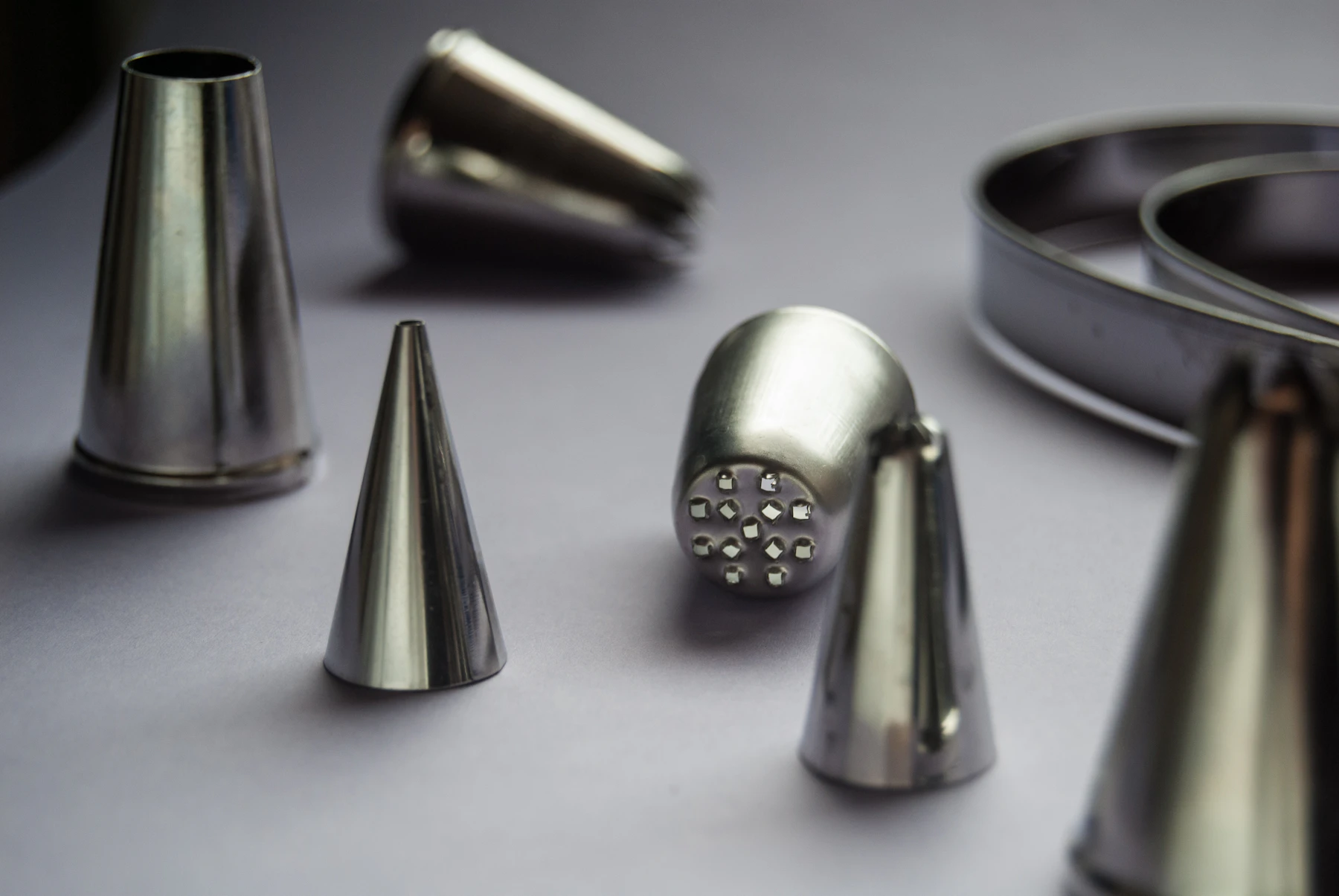 Stainless steel round, star and grass piping tips standing on a pale surface