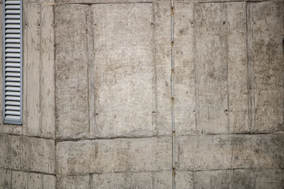 Close-up view of a concrete wall with a window and door, grid-like pattern visible