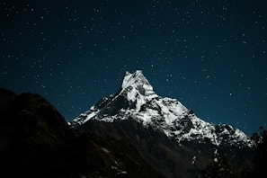 A cinematic 4k image of a towering snow-capped mountain under a deep midnight sky.
