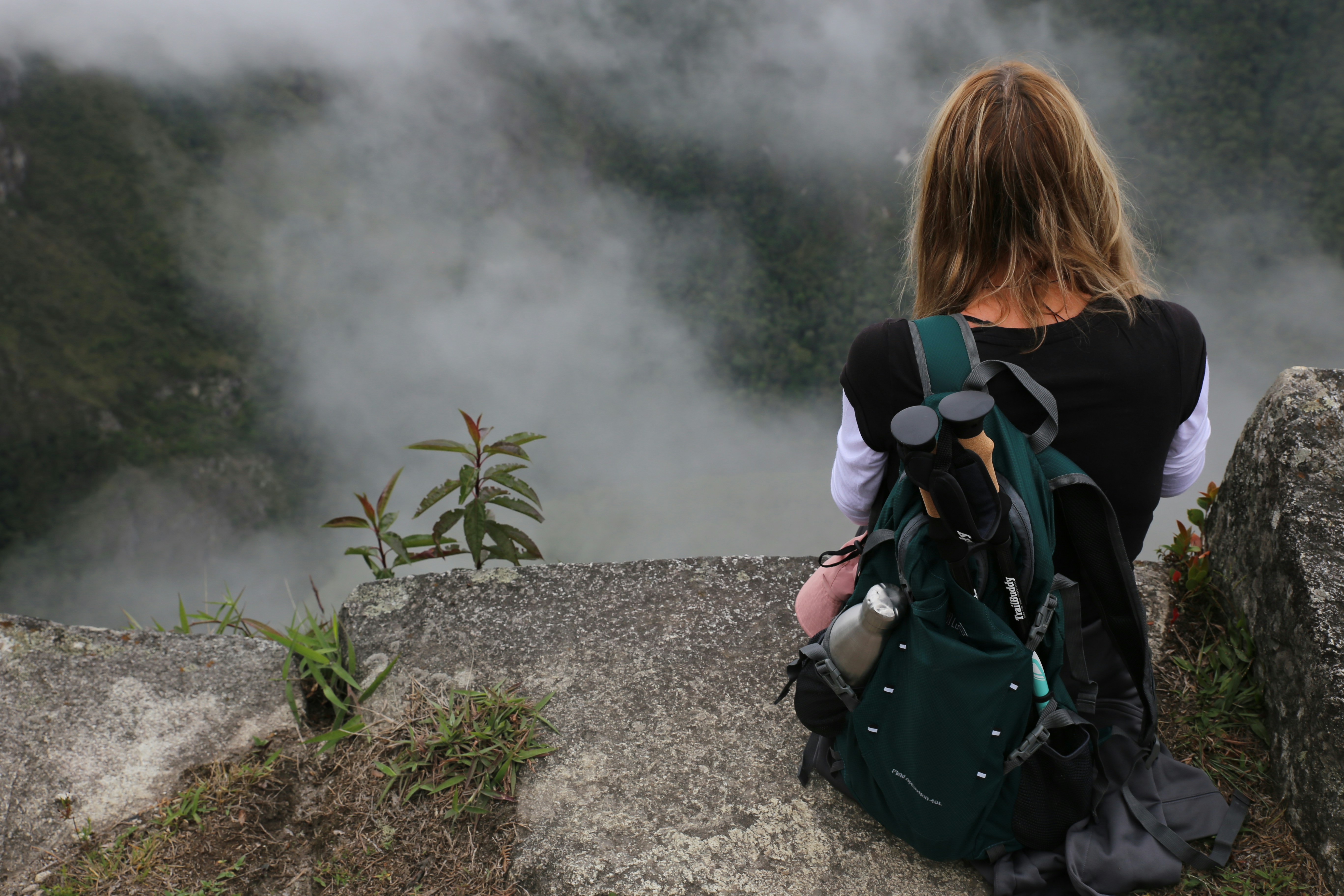 a person with a backpack looking at a foggy mountain