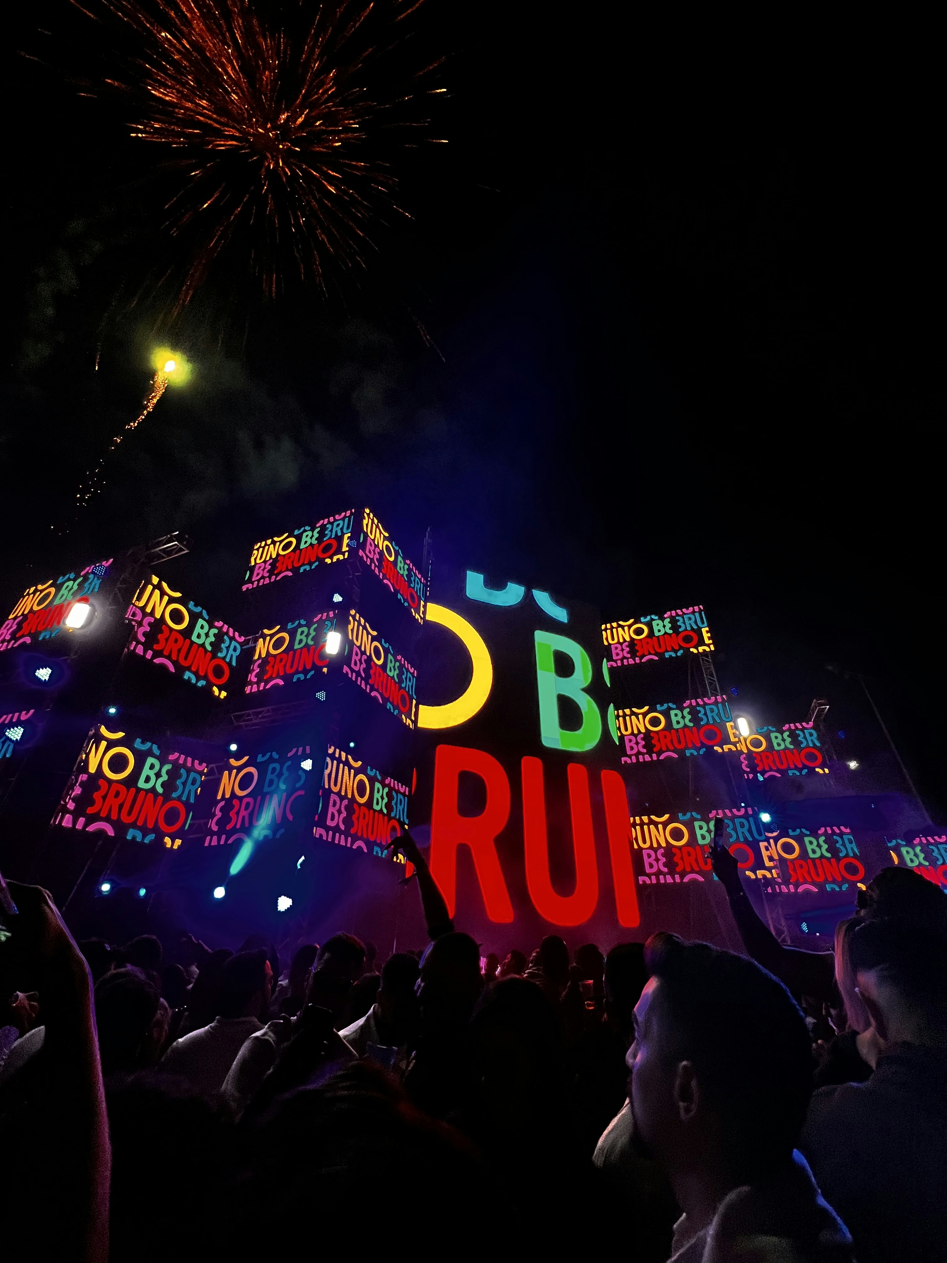 Evento nocturno con luces de colores y multitud disfrutando de experiencia en vivo