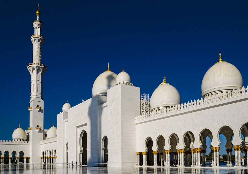 a white building with towers with Sheikh Zayed Mosque in the background