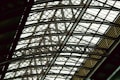 A complex and intricate metal framework forming an overhead structure, featuring interlocking beams and girders. The design conveys a sense of architectural strength and industrial sophistication.