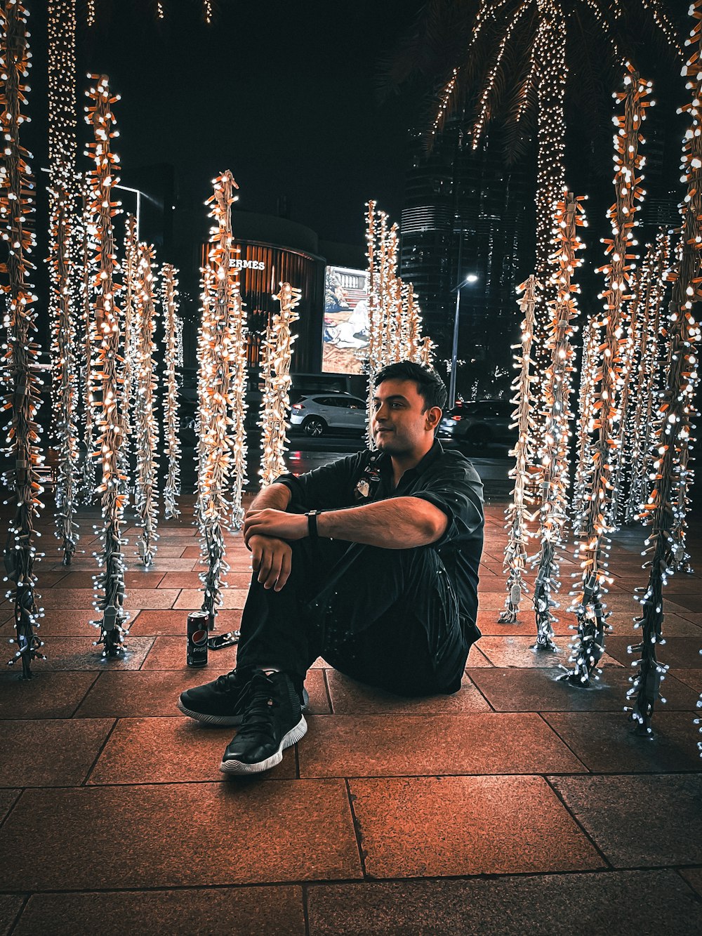 a man squatting on a sidewalk with lights on the side