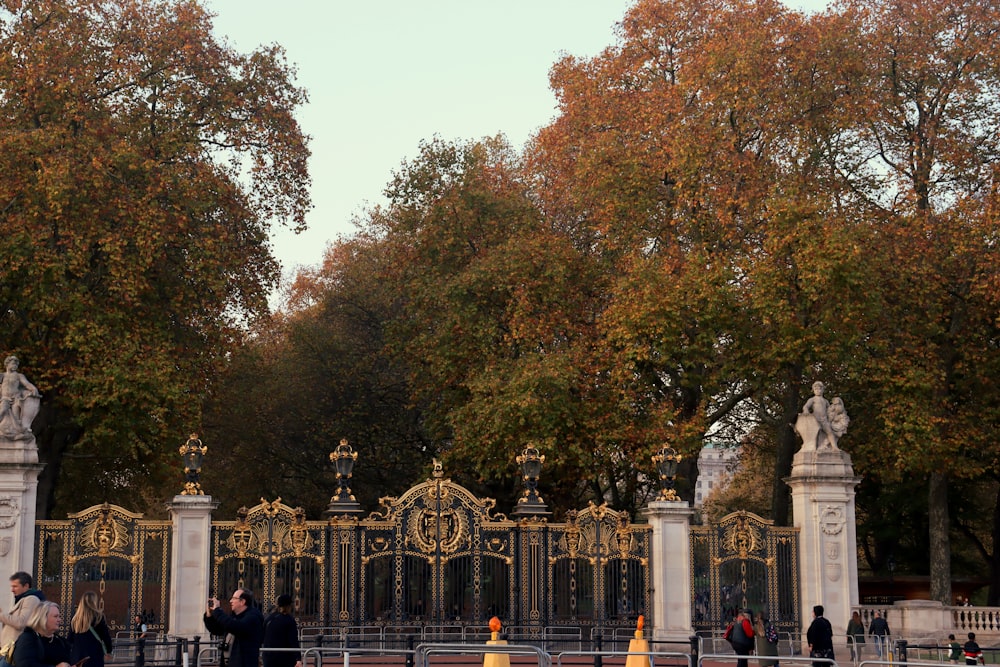 a group of people walking around a gated area with trees in the background