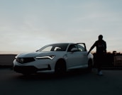 A smiling driver receiving help unlocking their car door at dusk.