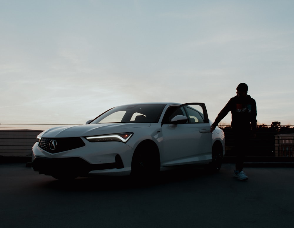 Un homme debout à côté d’une voiture blanche