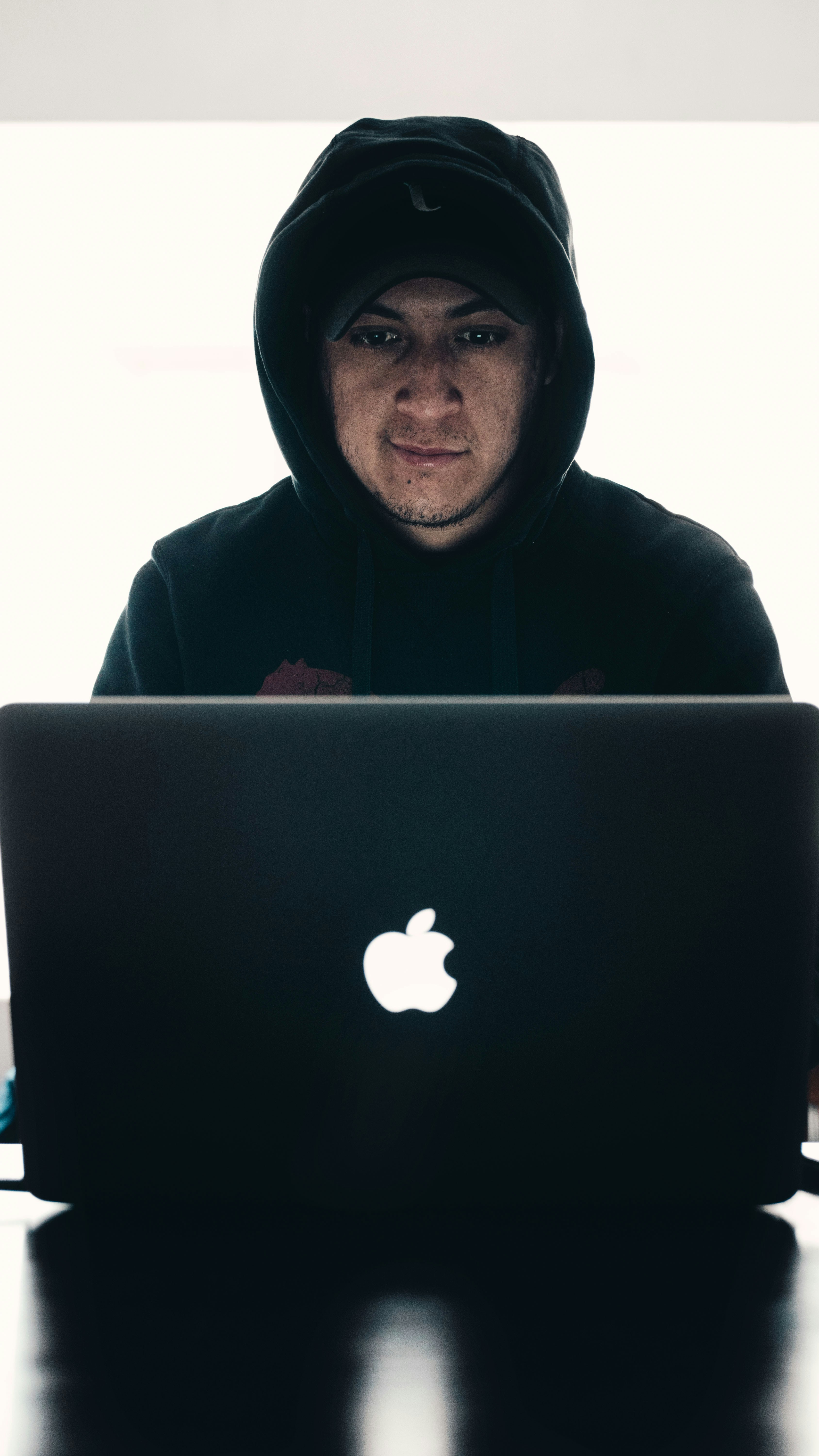 a man wearing a hoodie and looking at a laptop