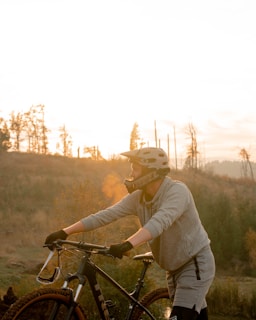 Athlete adjusting knee pads before a mountain biking session at sunset.