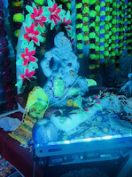 Colorful rangoli and floral decorations surrounding the temple-style Ganpati setup