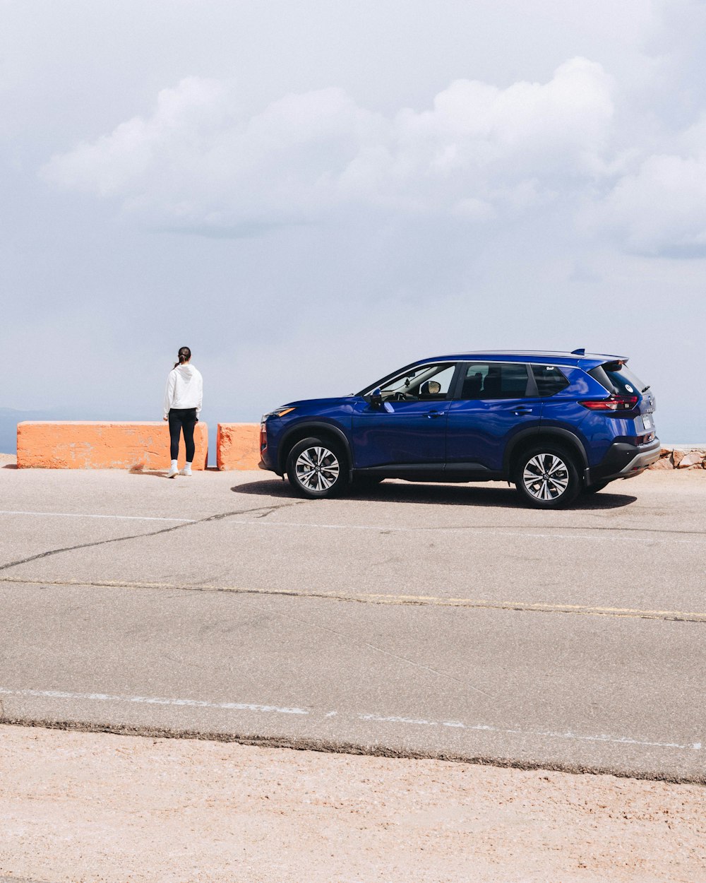 a person standing next to a blue car