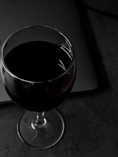 A person analyzing wine data on a laptop with a glass of wine beside them.