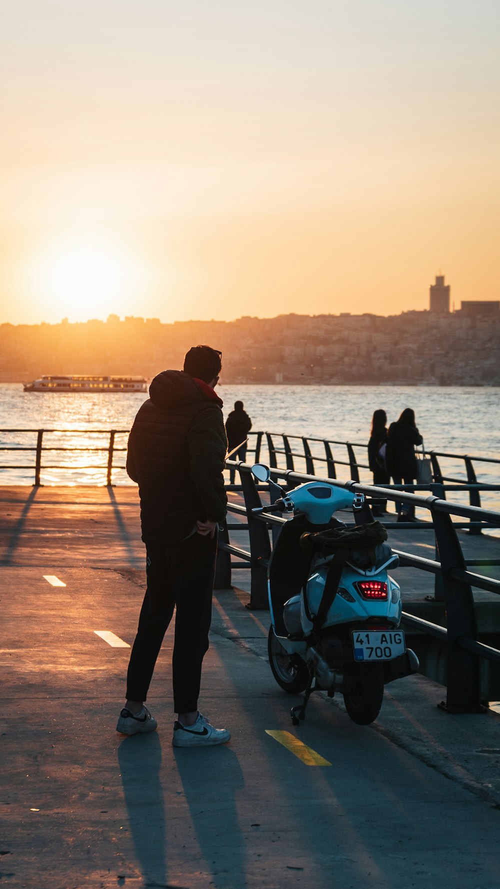 a person standing next to a scooter on a dock