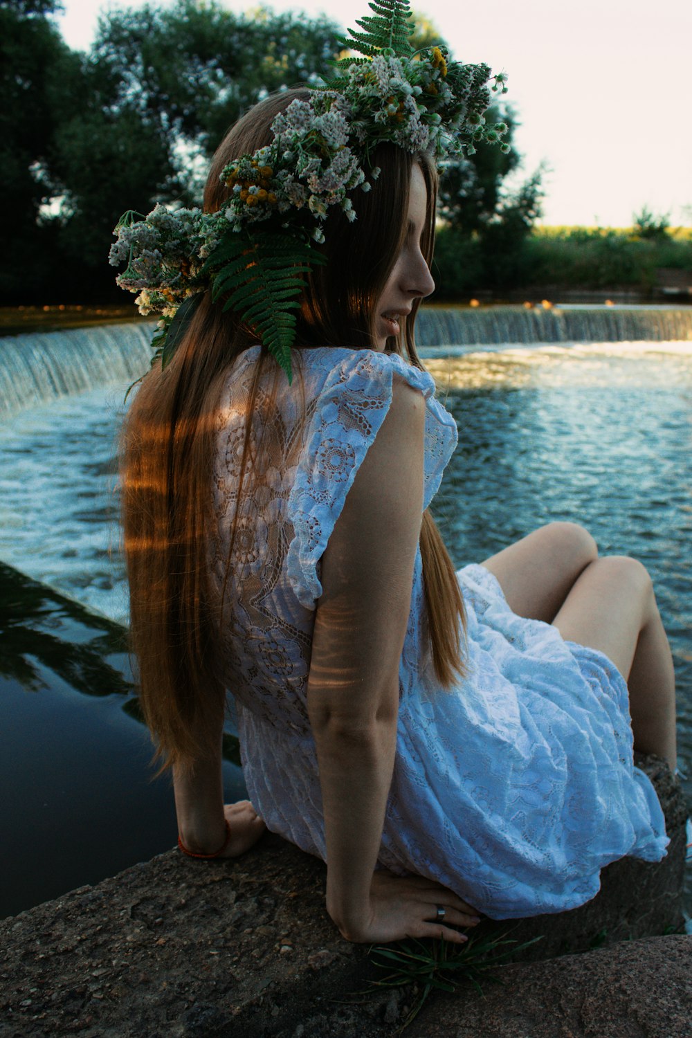 a person sitting on a rock by a body of water