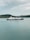A large ferry with the phrase 'We Love Indonesia' painted on the side is sailing in calm waters. In the background, there is a hilly shoreline covered with greenery under a cloudy sky.