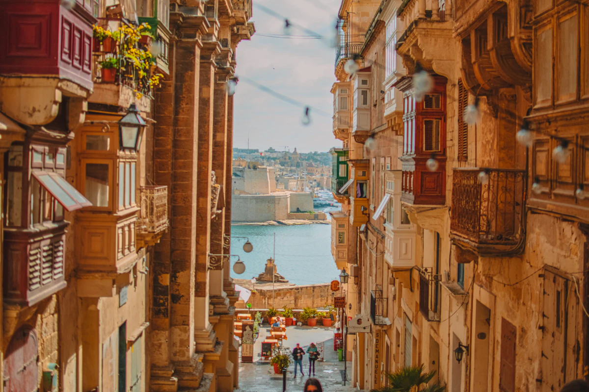 A steep Valletta street lined with colourful balconies descending towards the Grand Harbour