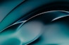 A smooth, abstract design featuring flowing curves and gradients. The image primarily uses shades of teal and black, creating a fluid and dynamic visual effect.