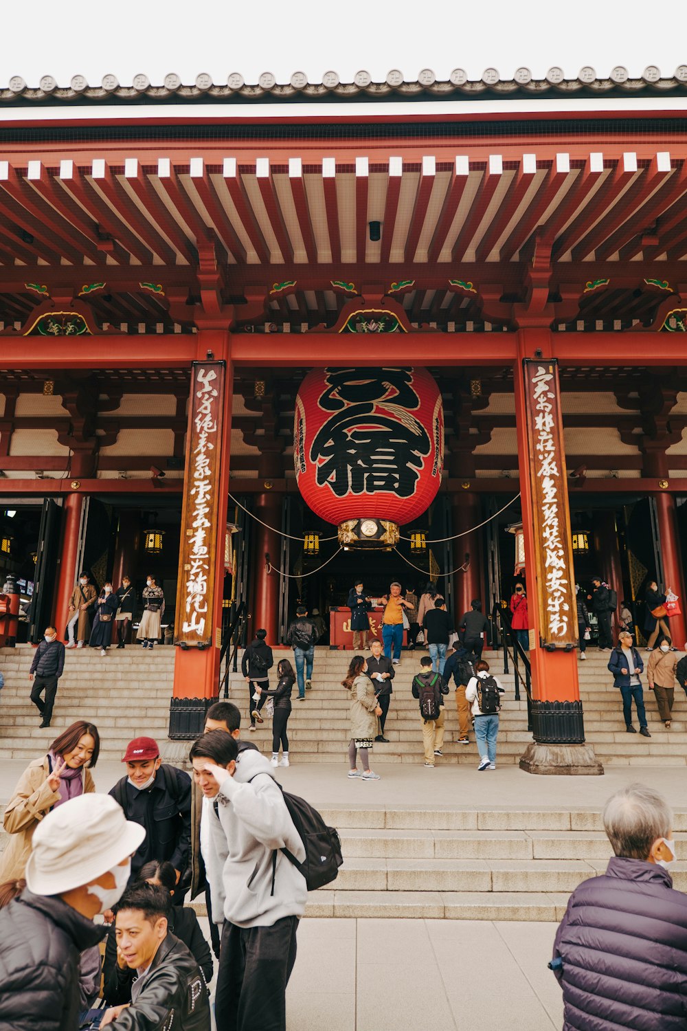 a group of people walking up stairs to a building with a large red and gold sign