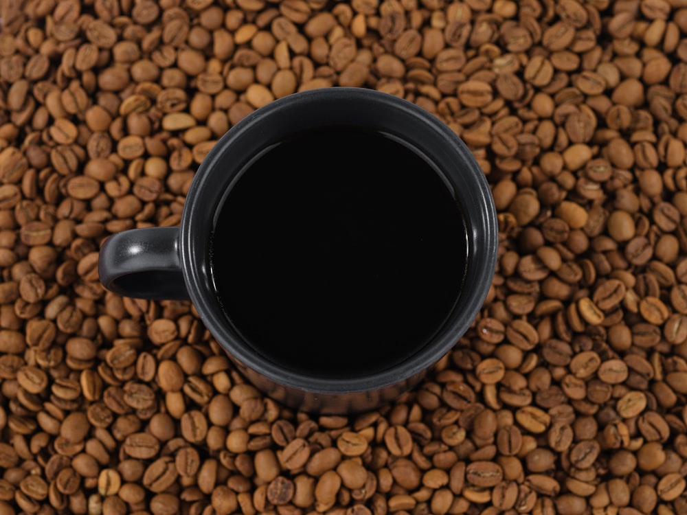 コーヒー豆の山の上の黒いマグカップ
