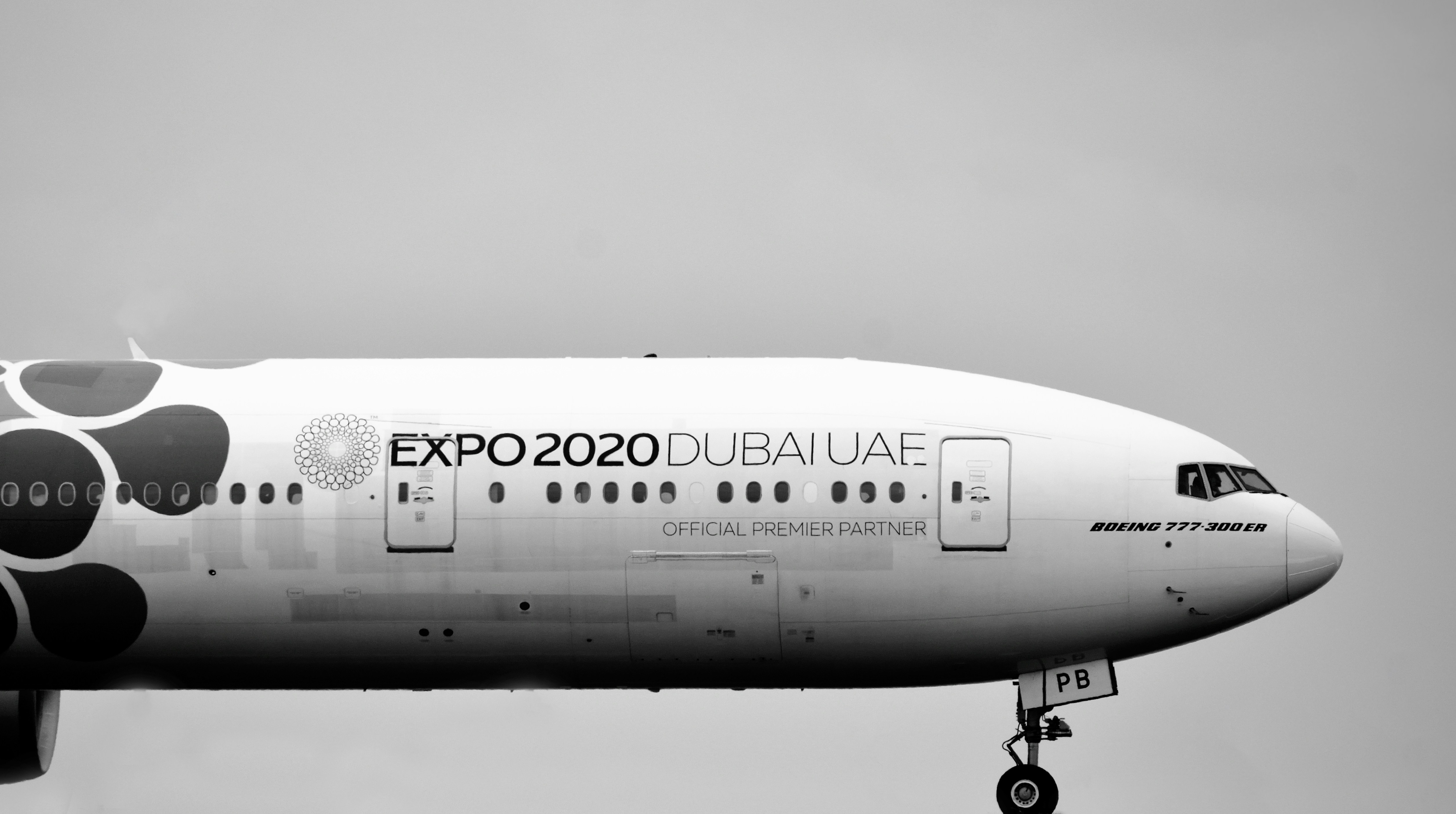 a large white airplane, Emirates 777-300ER running down Rwy 27 on its departure back to Dubai