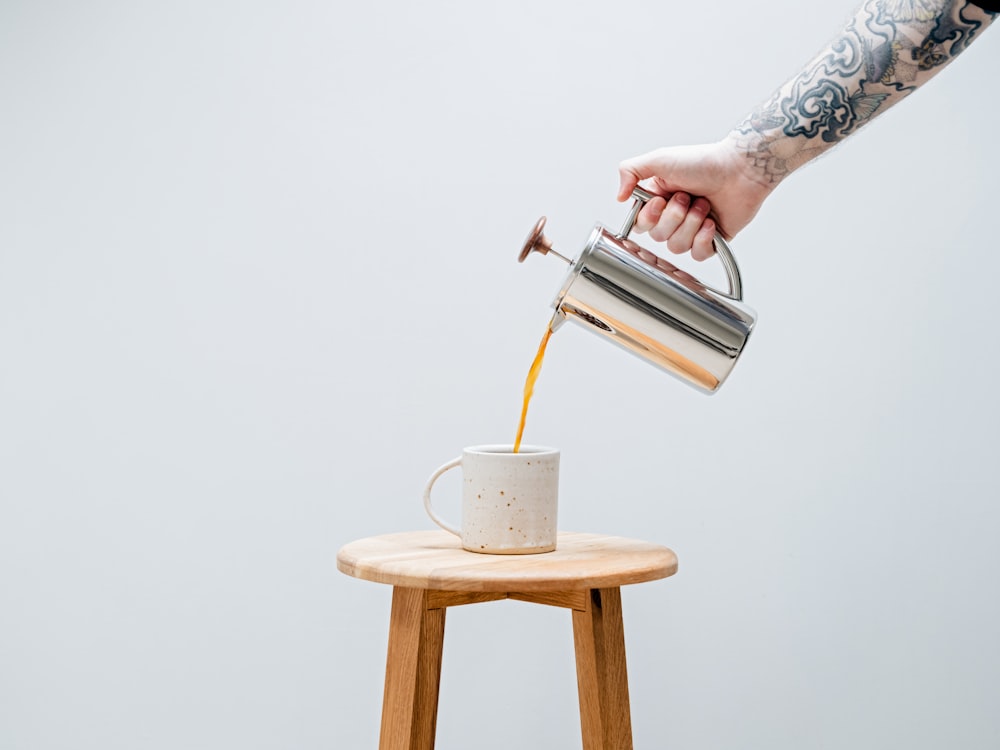 a hand pouring a liquid into a cup