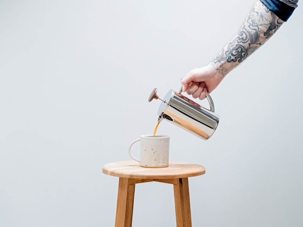 a hand pouring a cup of coffee