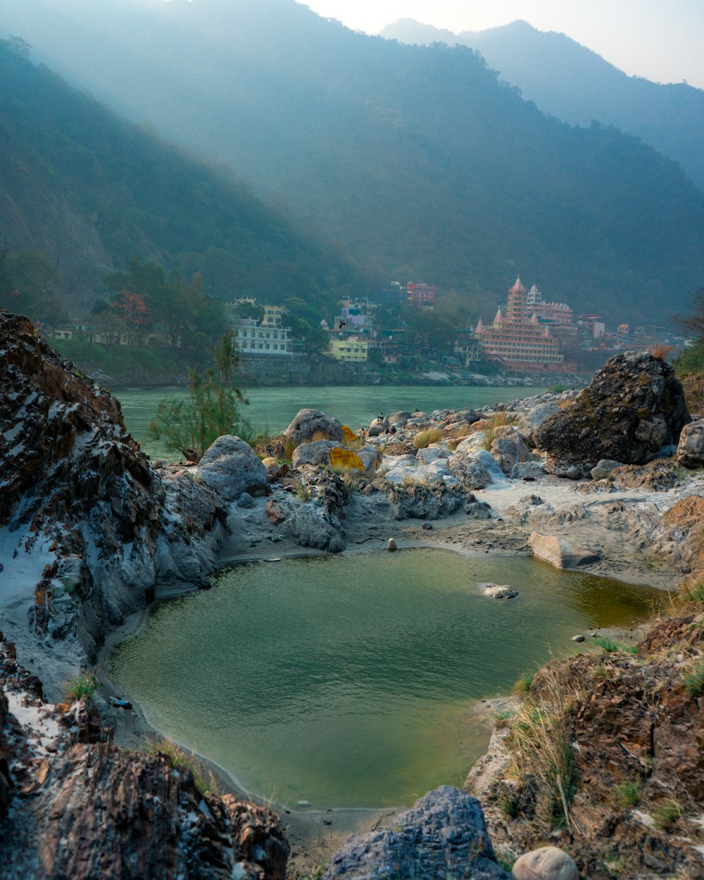 a body of water with buildings on the side and mountains in the background