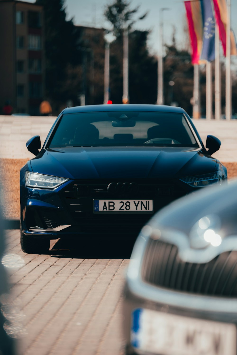 a couple of cars parked on a street with flags in the background