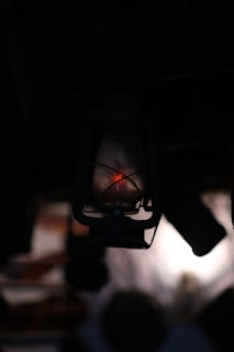 An antique lantern casting flickering orange light in a dark, wooded area