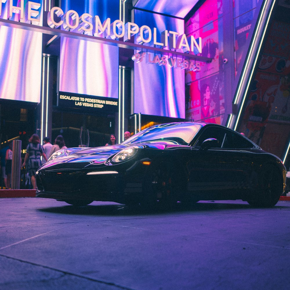 a black sports car parked in front of a store