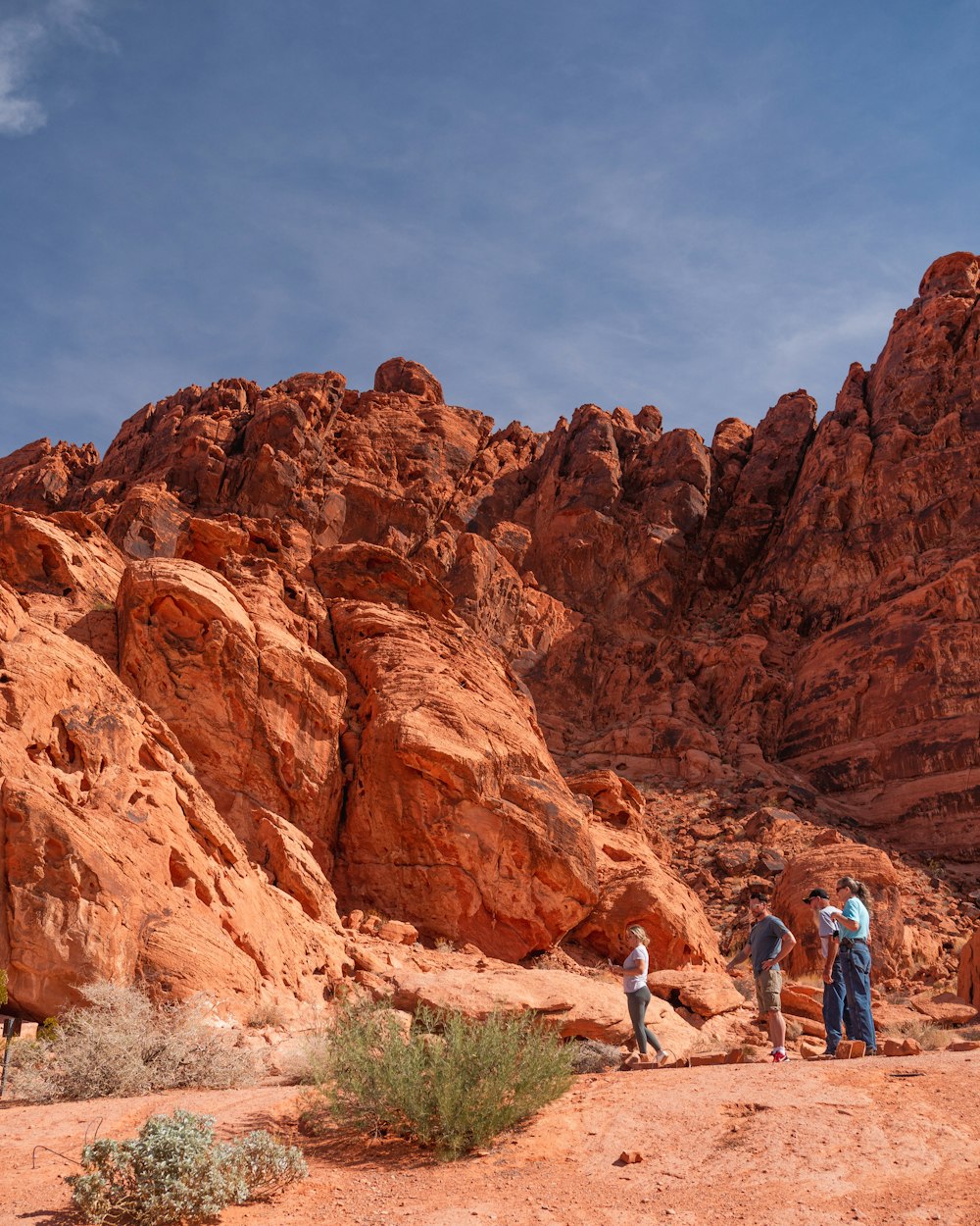a group of people standing in front of a large red rock formation