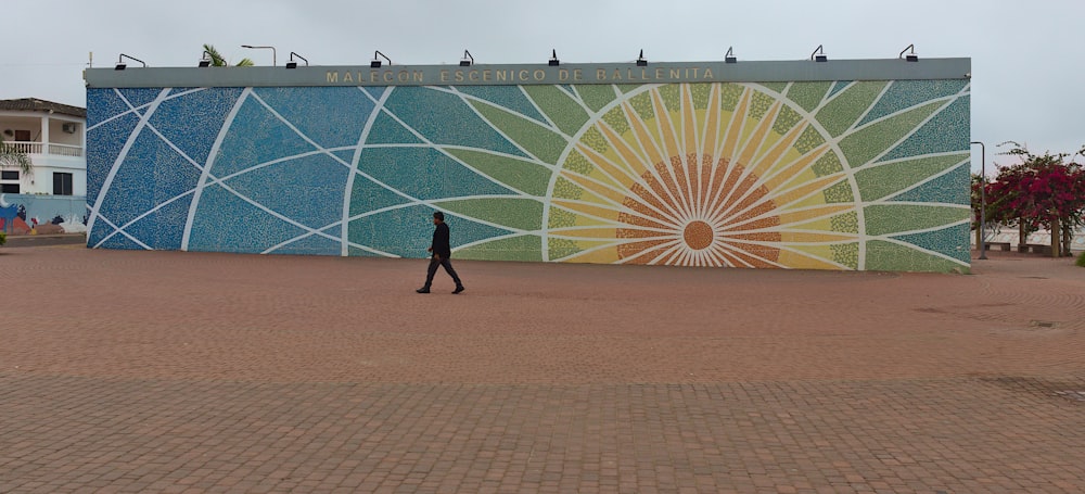 a person walking in front of a large building with a large glass wall