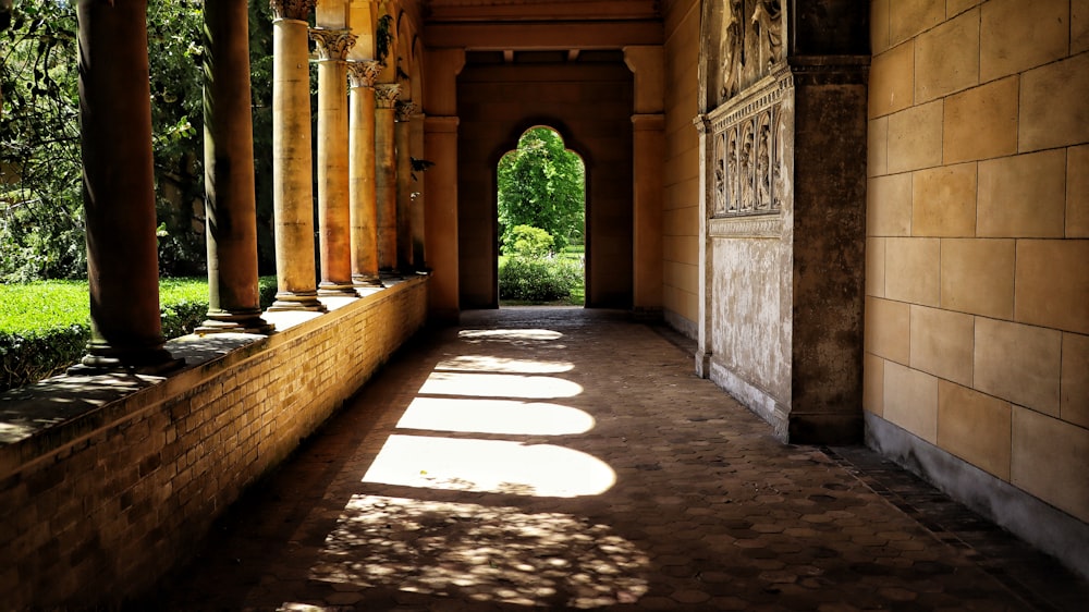 a walkway with pillars and a brick wall