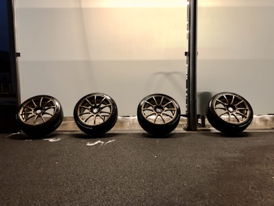 A row of freshly balanced car wheels lined up on the garage floor.