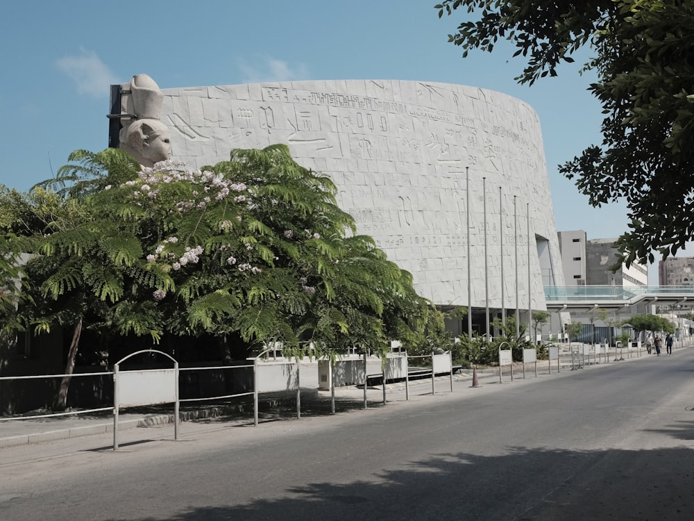 a large white building with a fence and trees in front of it