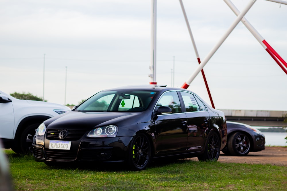 a black car parked on grass near a body of water