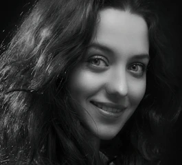 Black and white portrait of a smiling person with expressive eyes.