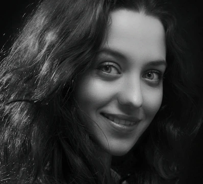Black and white portrait of a smiling person with expressive eyes.