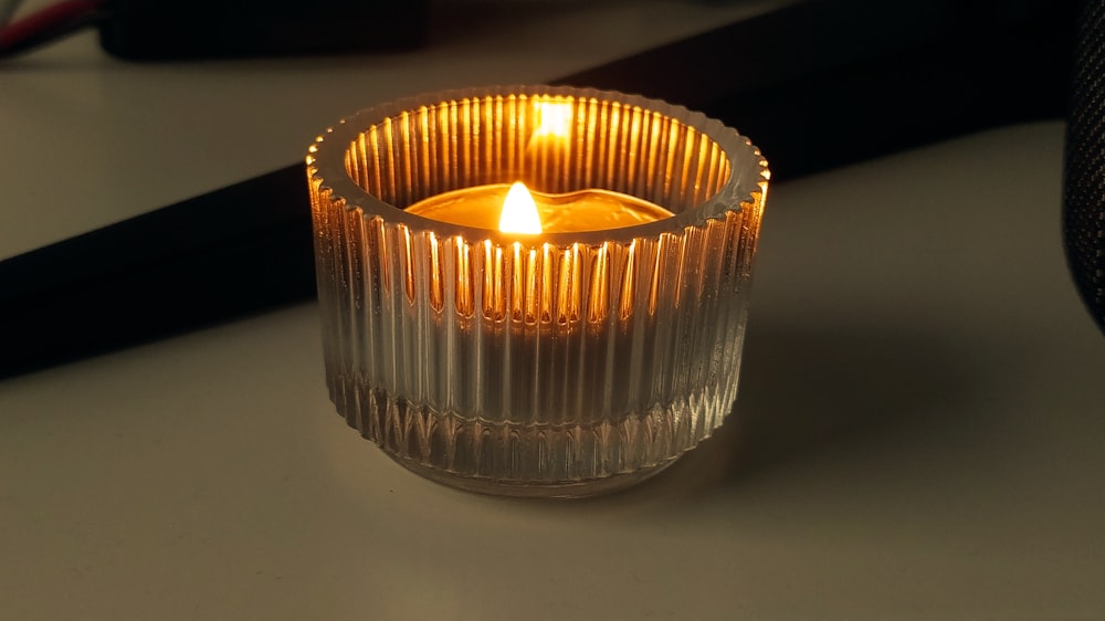 a lit candle in a glass jar
