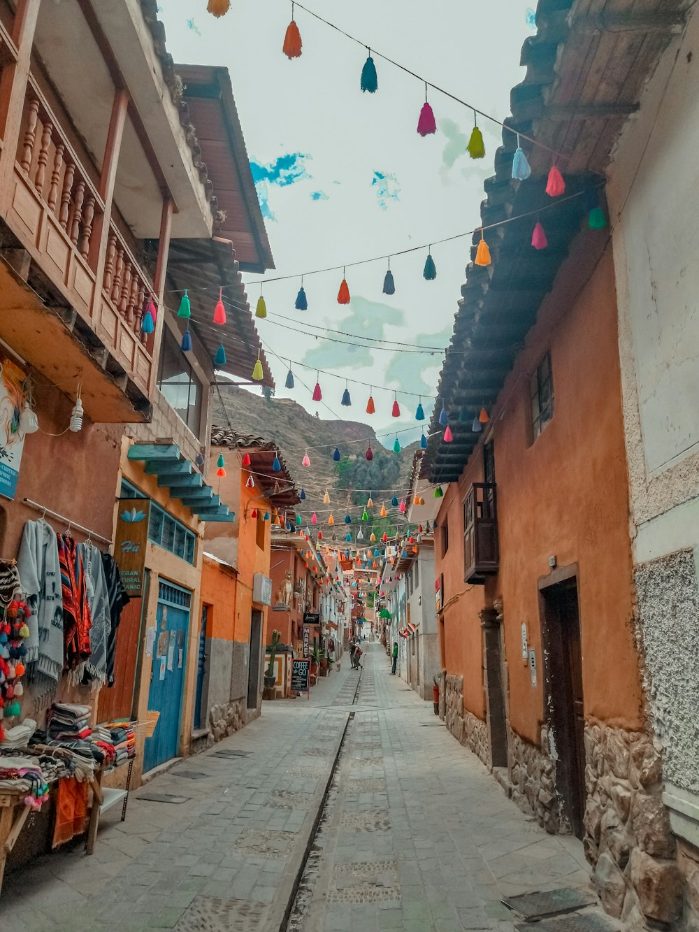 a narrow street with many flags from the ceiling