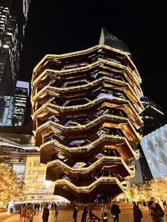 Nighttime view of the illuminated Dongdaemun Design Plaza with people enjoying the open space