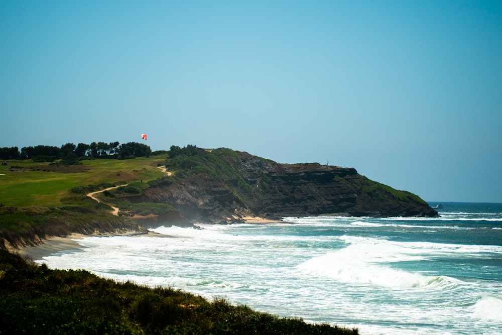 a grassy area with a body of water and a hill with a flag