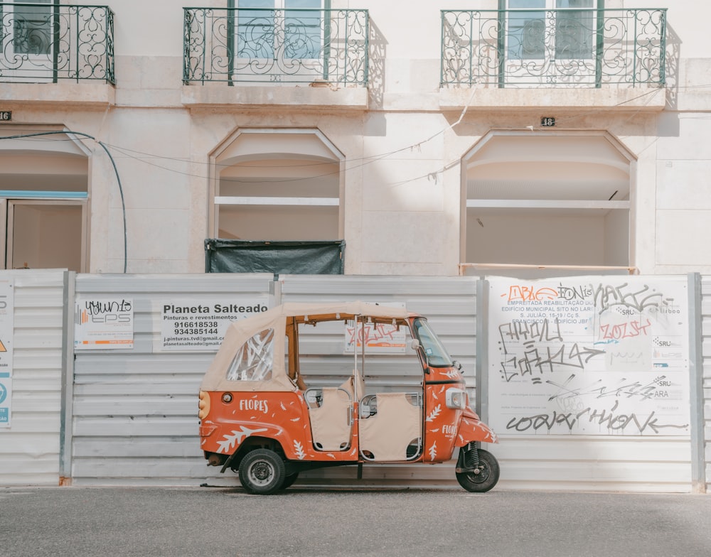 a small orange truck parked in front of a building