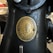 A close-up of an old sewing machine featuring a brass plate with the text 'The Singer Manfg Co' and 'Trade Mark.' The plaque includes an emblem with a threaded needle and decorative elements.